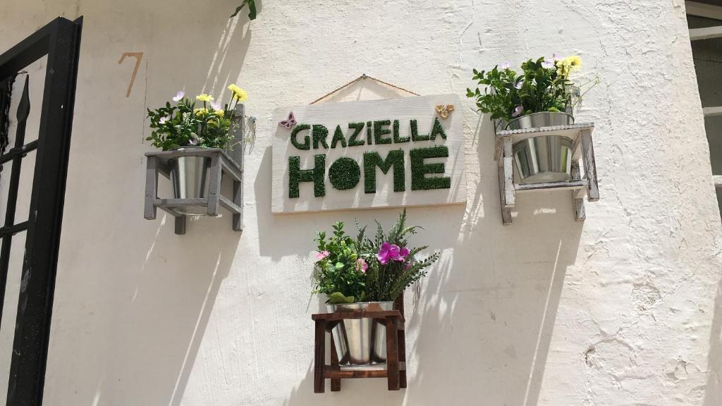 una pared blanca con tres macetas de flores y una señal en Graziella Home, en Martina Franca