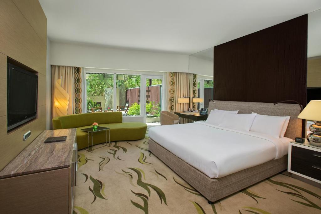 a bedroom with a large white bed and a television at Millennium Al Rawdah Hotel in Abu Dhabi