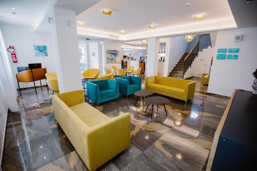 a lobby with yellow and blue chairs and stairs at Principe Alogna Hotel & SPA in Altavilla Milicia