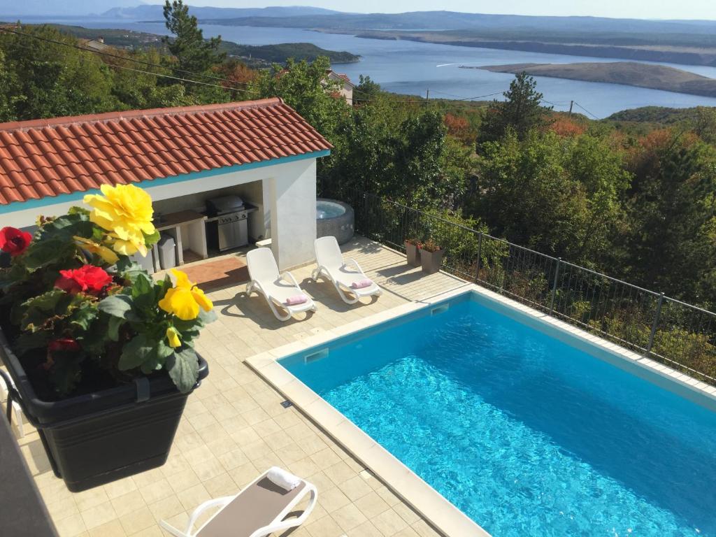 een zwembad met stoelen en bloemen op een patio bij Holiday Home Aqua in Šmrika