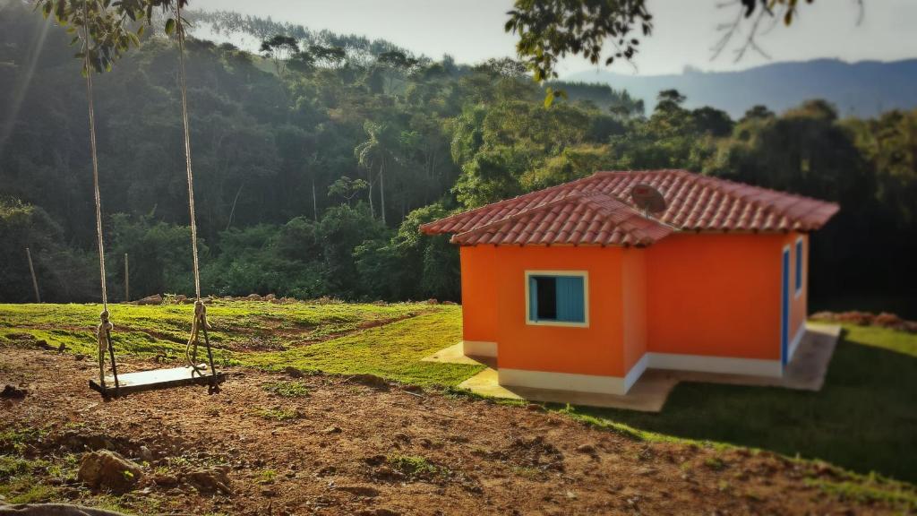 uma casa laranja num campo com um baloiço em Fortuna Casas de Campo em Socorro