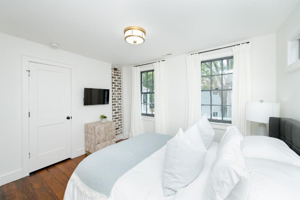 um quarto branco com uma cama e janelas em Guesthouse Charleston WEST 62 and 64 em Charleston