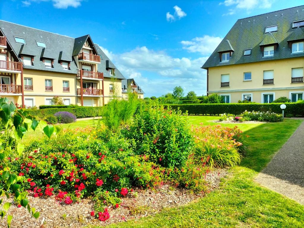 une rangée d'immeubles d'appartements avec des fleurs dans un jardin dans l'établissement Le Trianon, Magnifique appartement proche plage et Deauville, à Blonville-sur-Mer