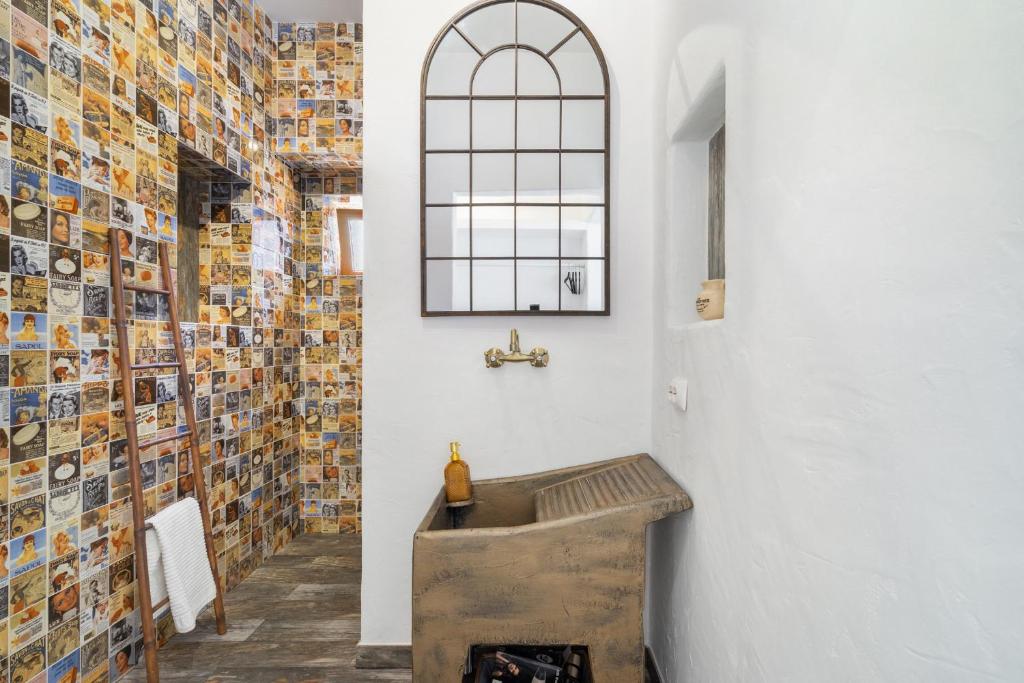 een badkamer met een houten wastafel en een muur met foto's bij Casa Celeiro in Estômbar