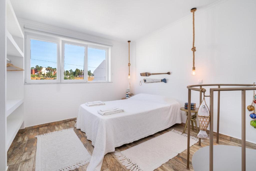 a white room with a bed and a window at Casa Cachalote in Ferragudo