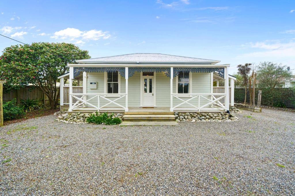 a white house with a porch on a gravel driveway at Pendreigh Cottage - Martinborough Holiday Home in Martinborough 