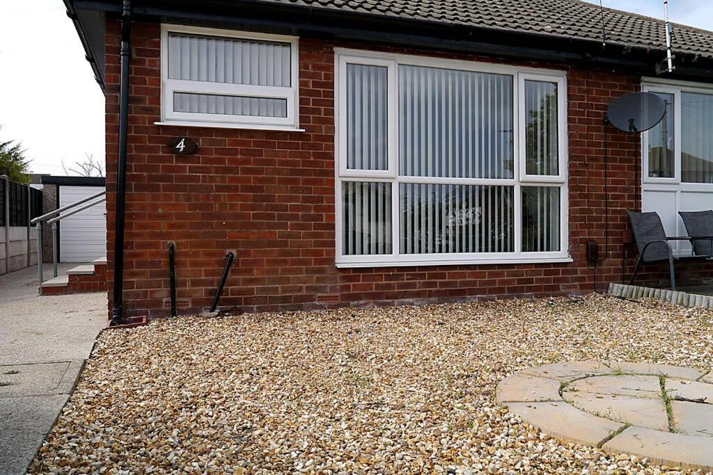 a brick house with two windows and a patio at Bee Bungalow in Blackpool in Blackpool