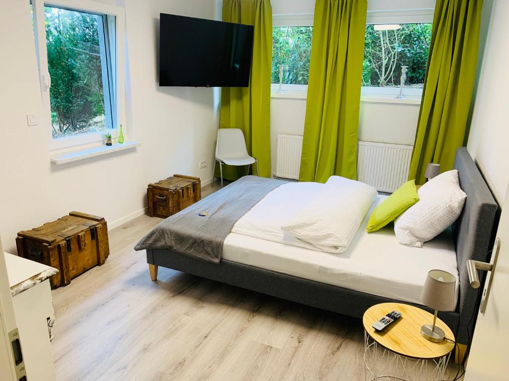a bedroom with a bed with green curtains and a flat screen tv at Appartement Apelern (A2) - 2 Zimmer, Badewanne, Terrasse, Netflix in Apelern