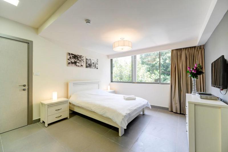 a white bedroom with a bed and a window at Dizengoff Inn Apartments in Tel Aviv