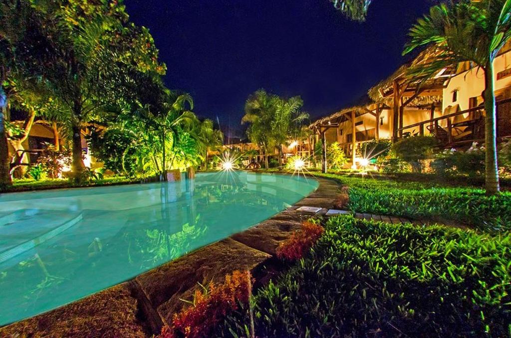 a swimming pool in front of a resort at night at Le Zahir Lodge in Ambatoloaka