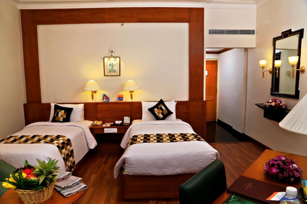 ein Hotelzimmer mit 2 Betten und einem Tisch in der Unterkunft Gokulam Park in Kochi