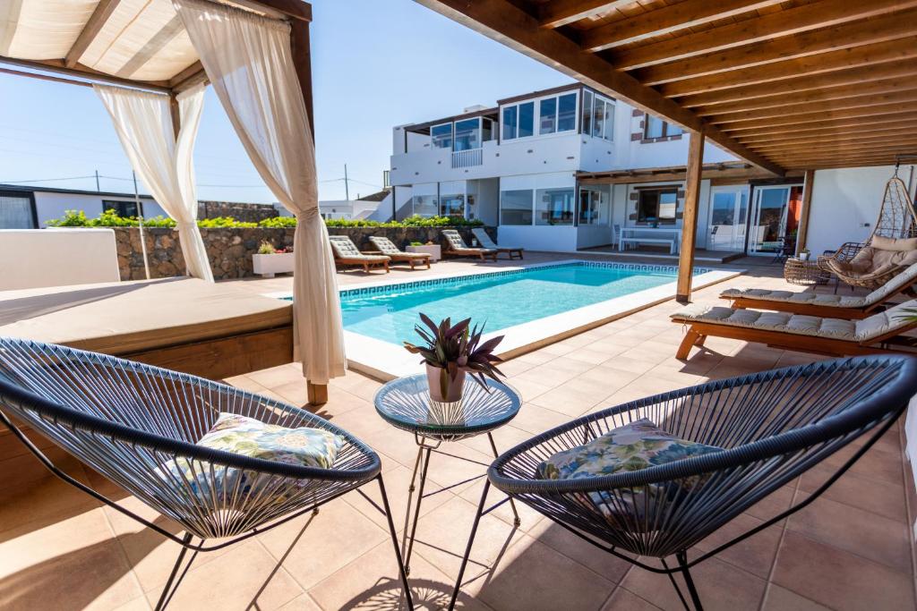 an outdoor patio with chairs and a swimming pool at Apartamentos El Callao II Suites in La Asomada