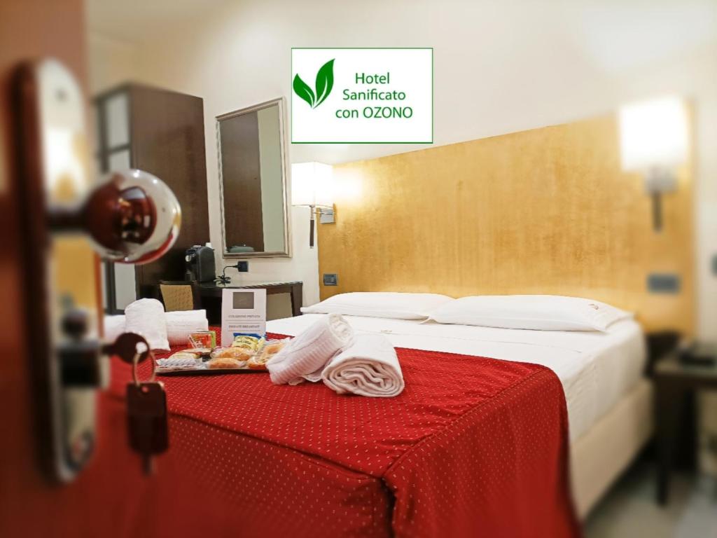 a room with a bed with a red table with towels at Hotel Fiorella Milano in Milan