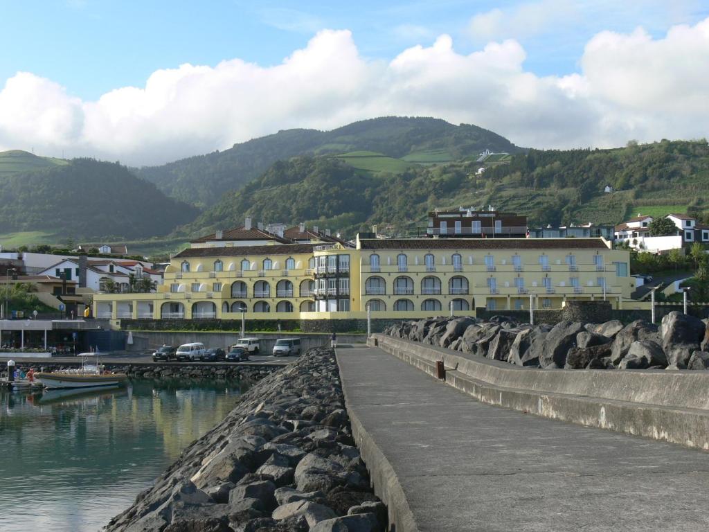 a large yellow building next to a body of water at Vinha da Areia Beach Hotel in Vila Franca do Campo