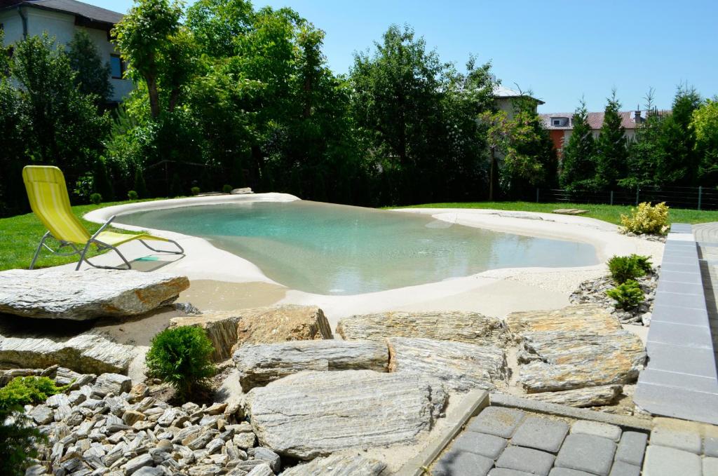 a pool of water with a yellow chair and rocks at Willa Rubinia in Iwonicz-Zdrój