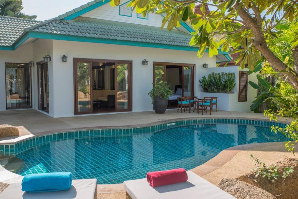 a villa with a swimming pool in front of a house at Hua Thanon2 in Laem Set Beach