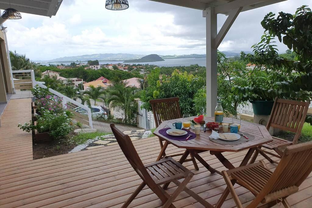 a table and chairs on a deck with a view at Petit Refuge in Les Trois-Îlets