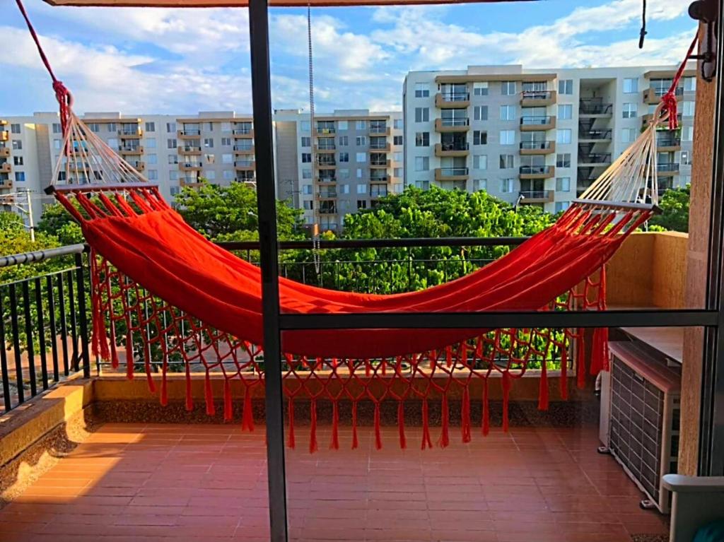 a red hammock hanging on a balcony with buildings at PeñalisaKapoSalSar in Girardot