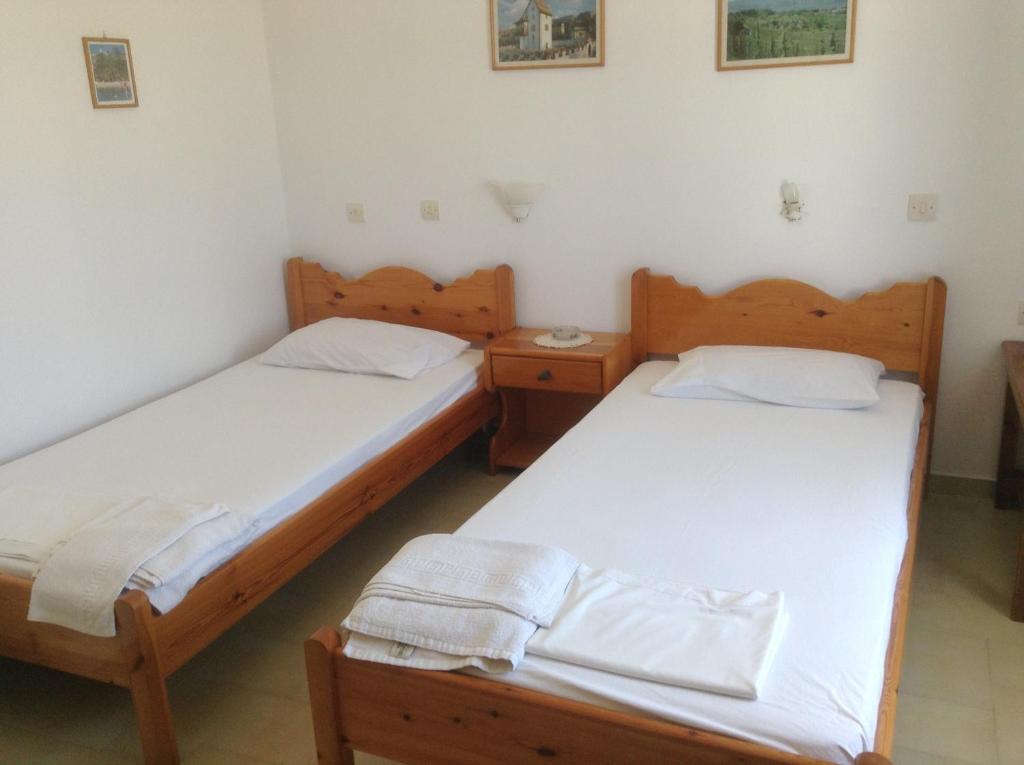 two twin beds in a room with two tables at Rania Apartments in Antiparos Town
