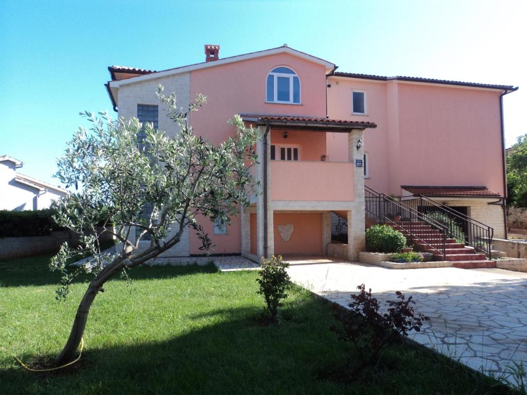 una casa rosa con un árbol delante en Apartments Vera, en Ližnjan
