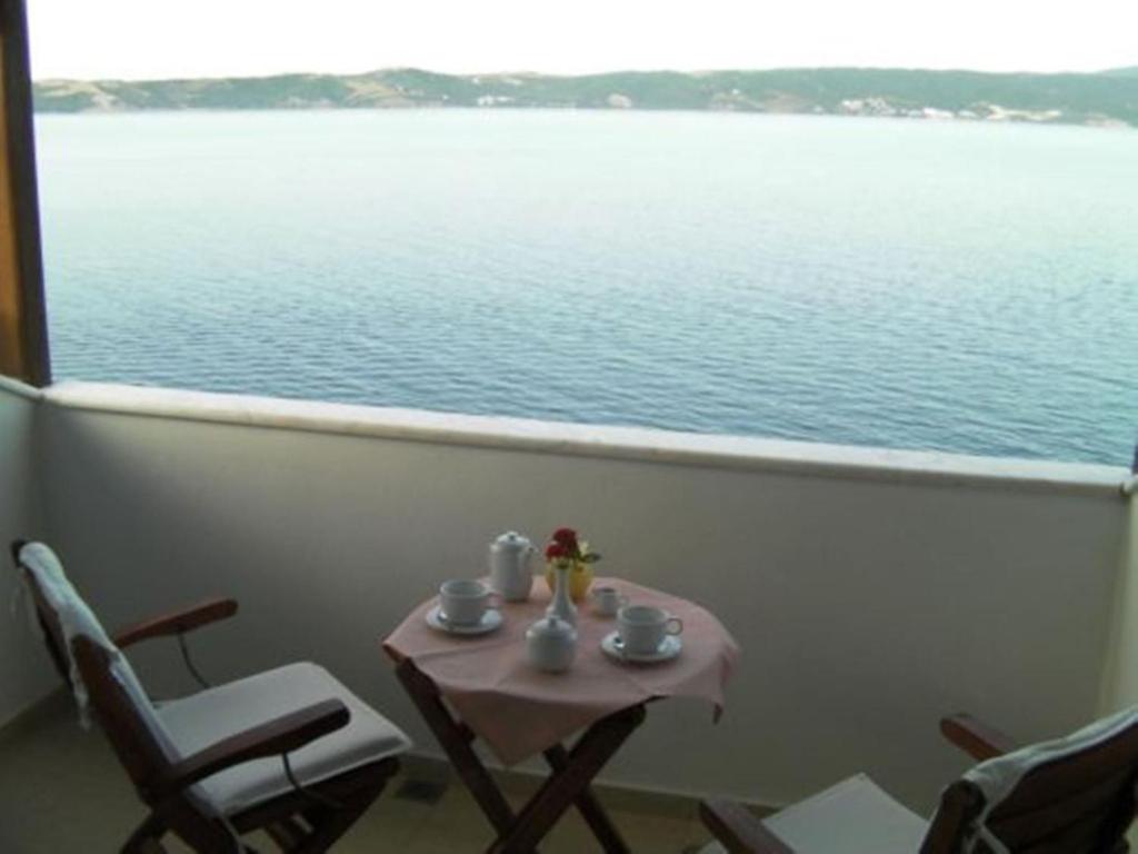 a table and chairs on a balcony with a view of the water at Ammouliani Hotel in Ammouliani