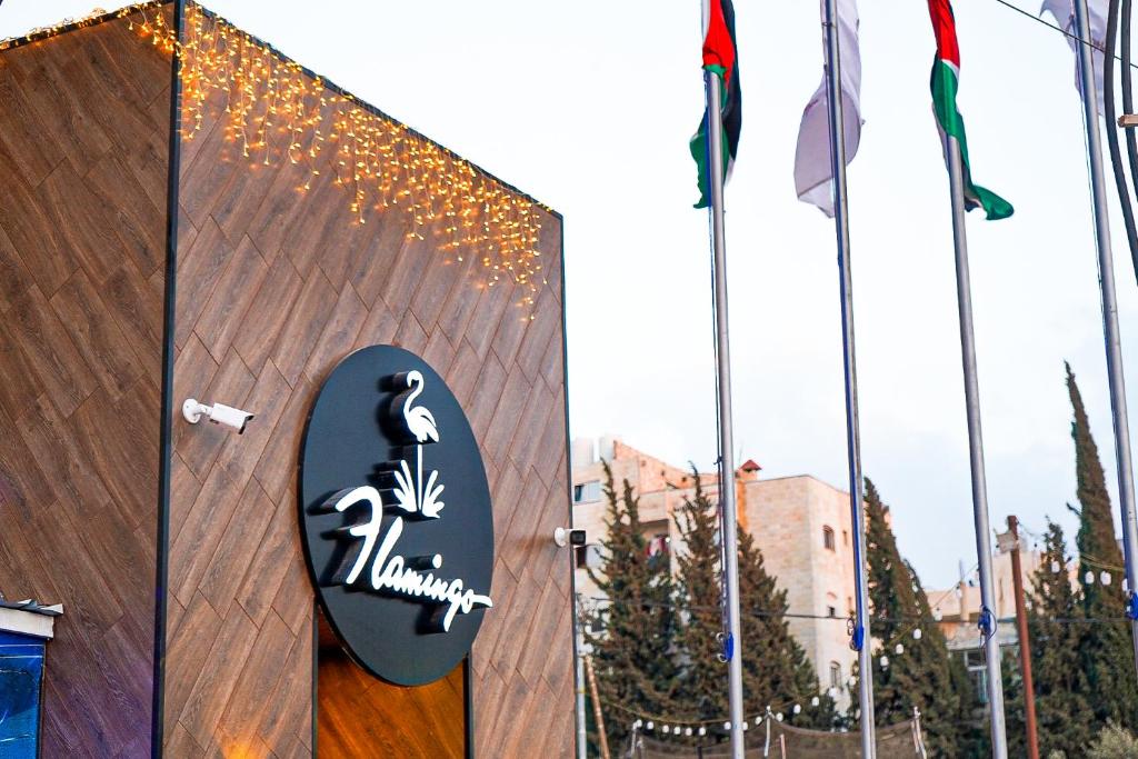 un panneau sur le côté d'un bâtiment avec drapeaux dans l'établissement flamingo hotel irbid, à Zabdah