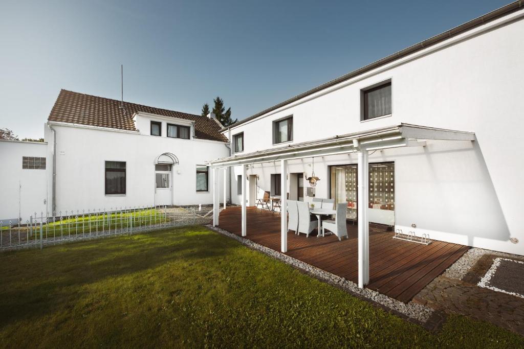 une maison blanche avec une terrasse et une pelouse dans l'établissement Airport Messe Hotel - Messeschlaf, à Düsseldorf