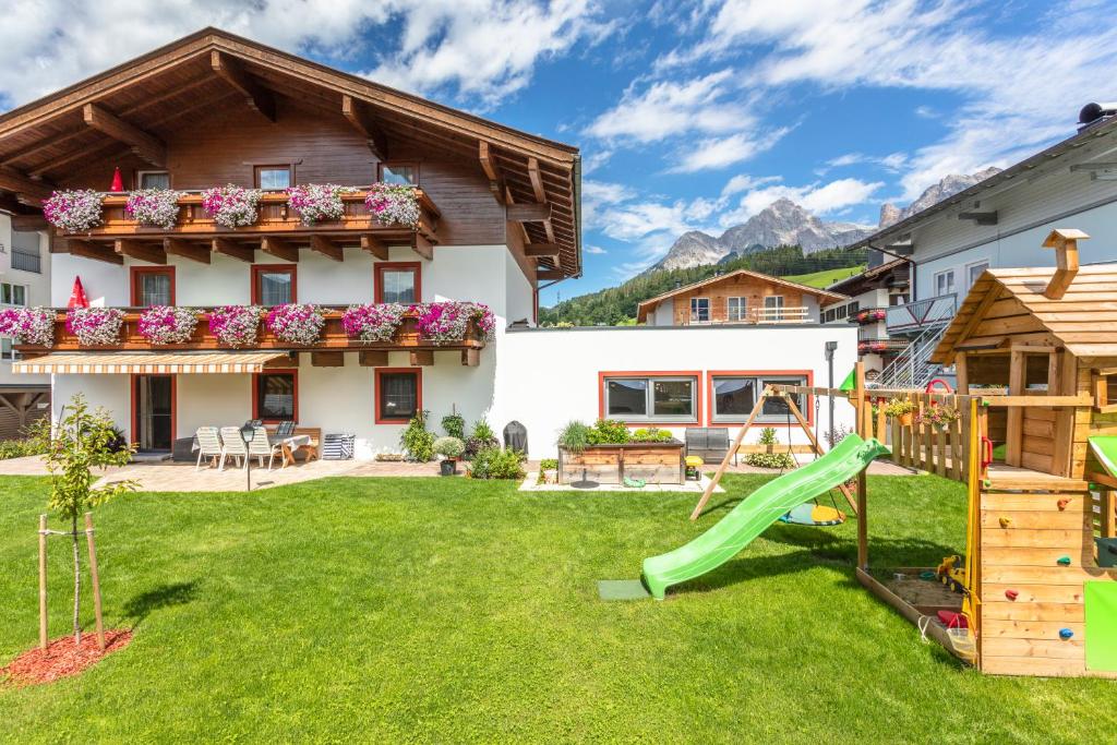 un patio trasero con un tobogán y una casa en Appartements Wagnerhaus en Maria Alm am Steinernen Meer