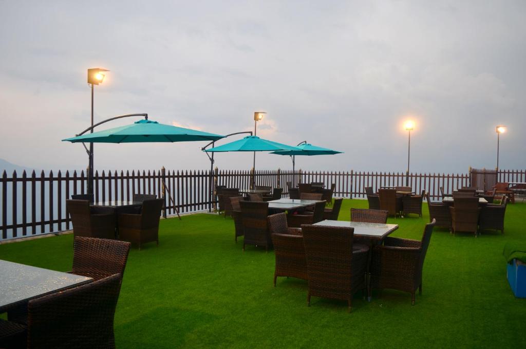 un restaurante con mesas y sillas con sombrillas azules en Holiday Grand Resort Bhurban, en Murree