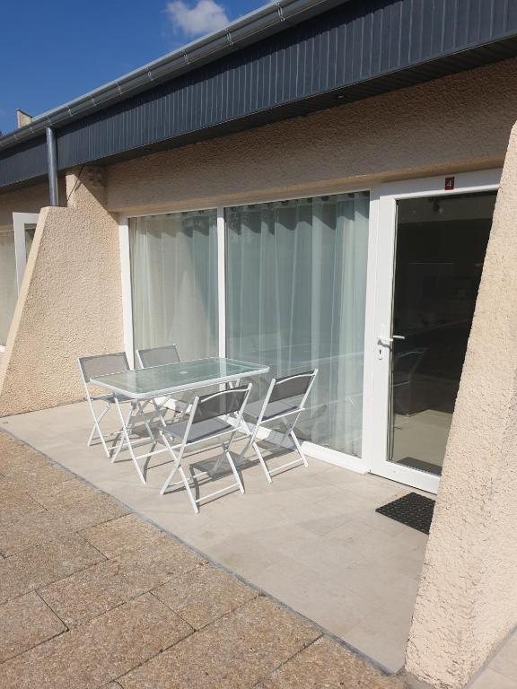 une table en verre et deux chaises sur la terrasse dans l'établissement Clos du Béron- Appartement meublé de tourisme, à Cappelle-en-Pévèle