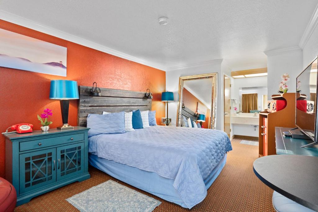 Americana Inn Motel في سووث سان فرانسيسكو: غرفة نوم بسرير وجدار برتقالي