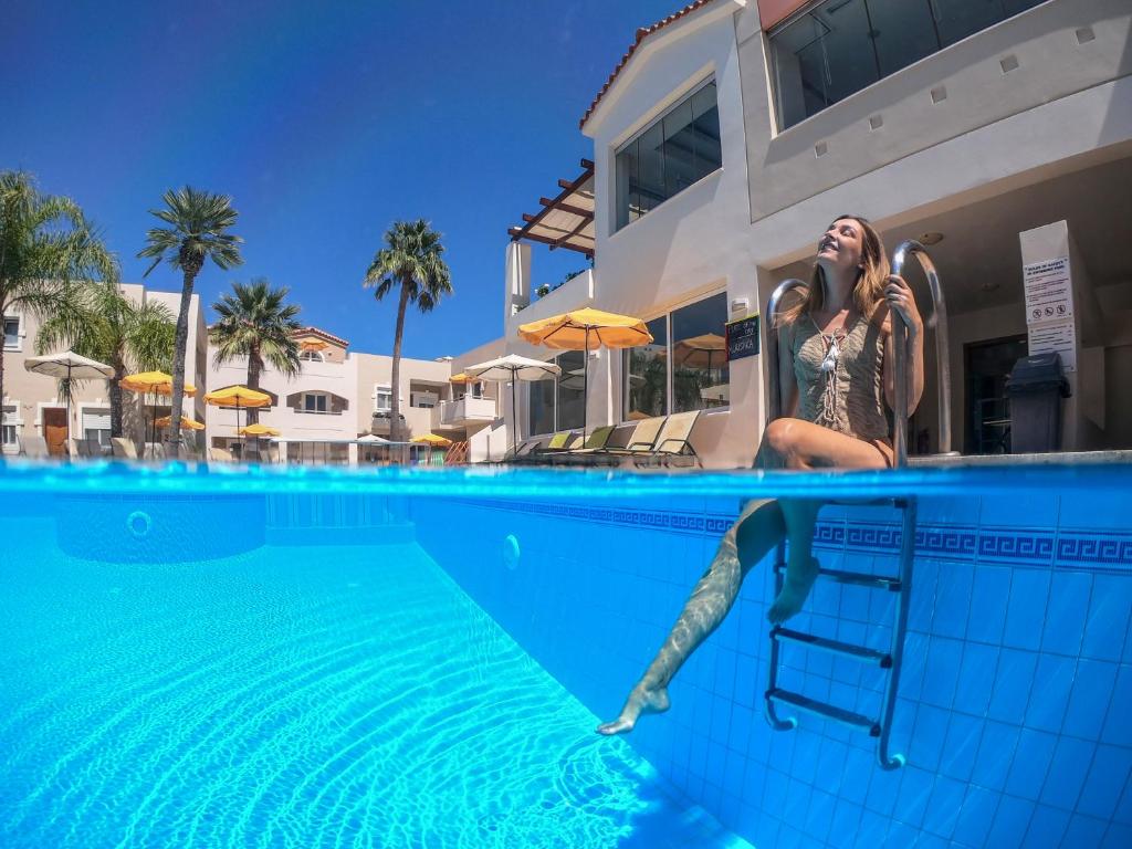 Una donna seduta su una scala in piscina di Toxo Hotel a Plataniás