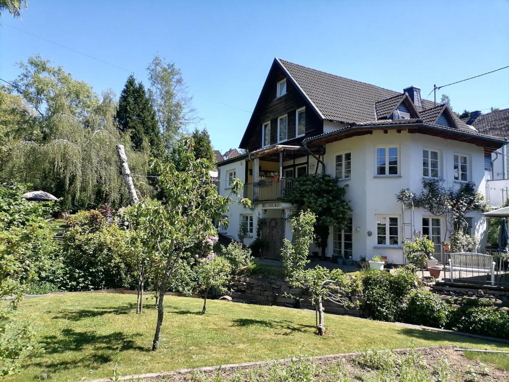 Une grande maison blanche avec des arbres dans la cour dans l'établissement Ferienwohnnung Herling, à Siegen