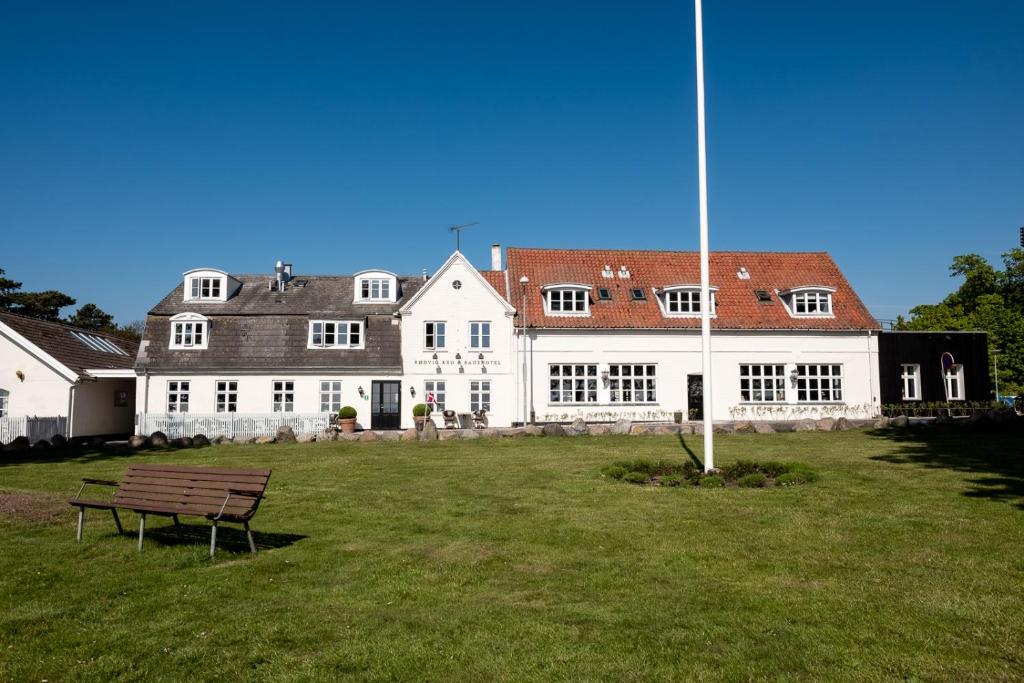 a large white building with a bench in front of it at Rødvig Kro og Badehotel in Rødvig