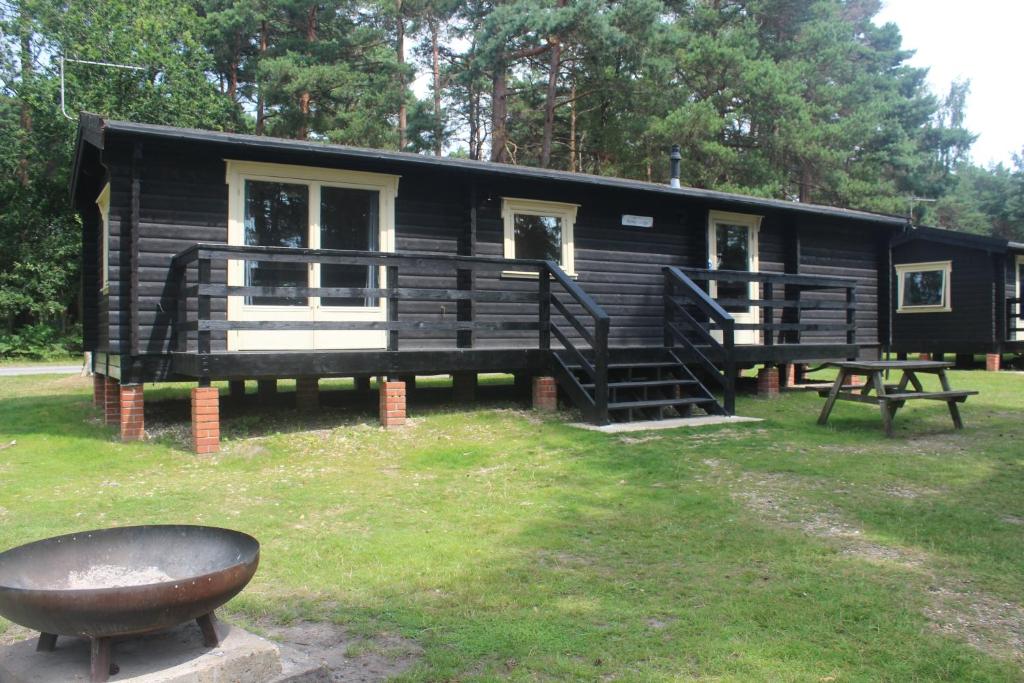 a black cabin with a picnic table in front of it at Avon Tyrrell Outdoor Activity Centre in Bransgore