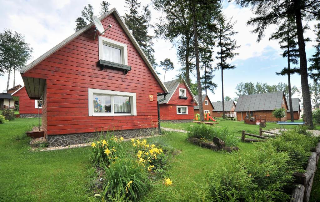 une maison rouge avec une cour fleurie dans l'établissement APLEND Chaty Tatry Holiday, à Veľký Slavkov