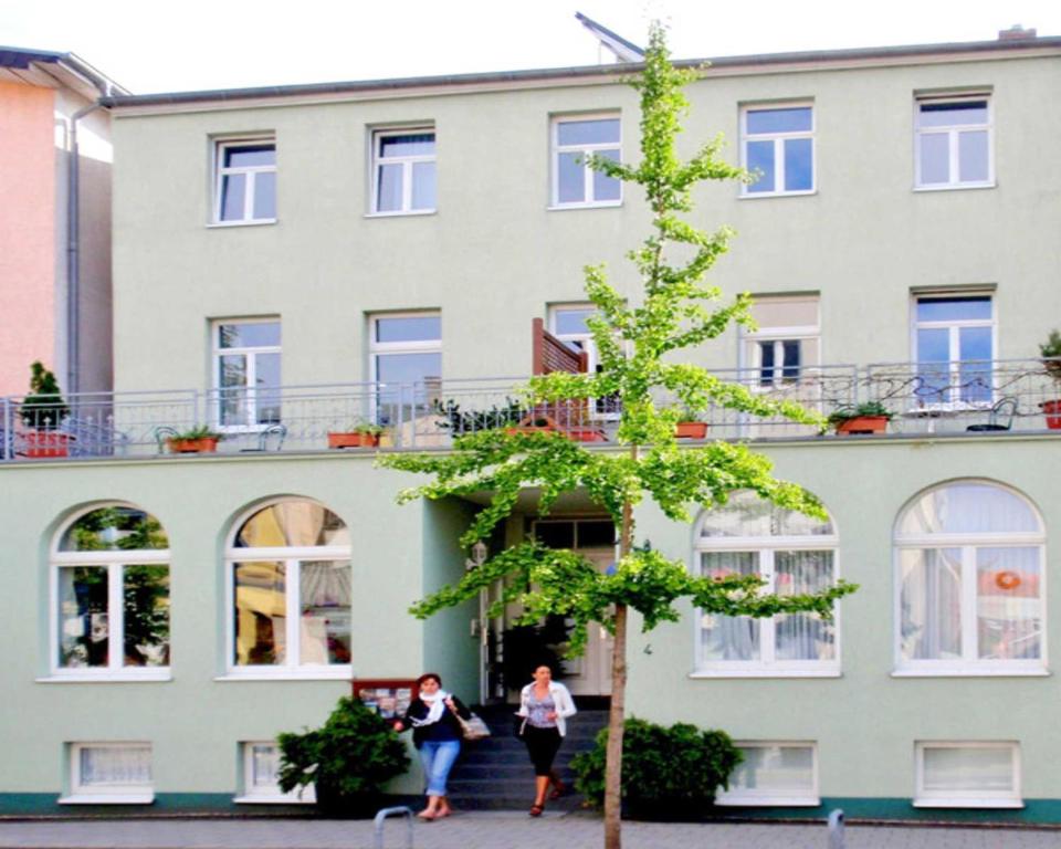 dos mujeres caminando delante de un edificio en Hotel Garni Villa Ostseegruss Obje, en Warnemünde