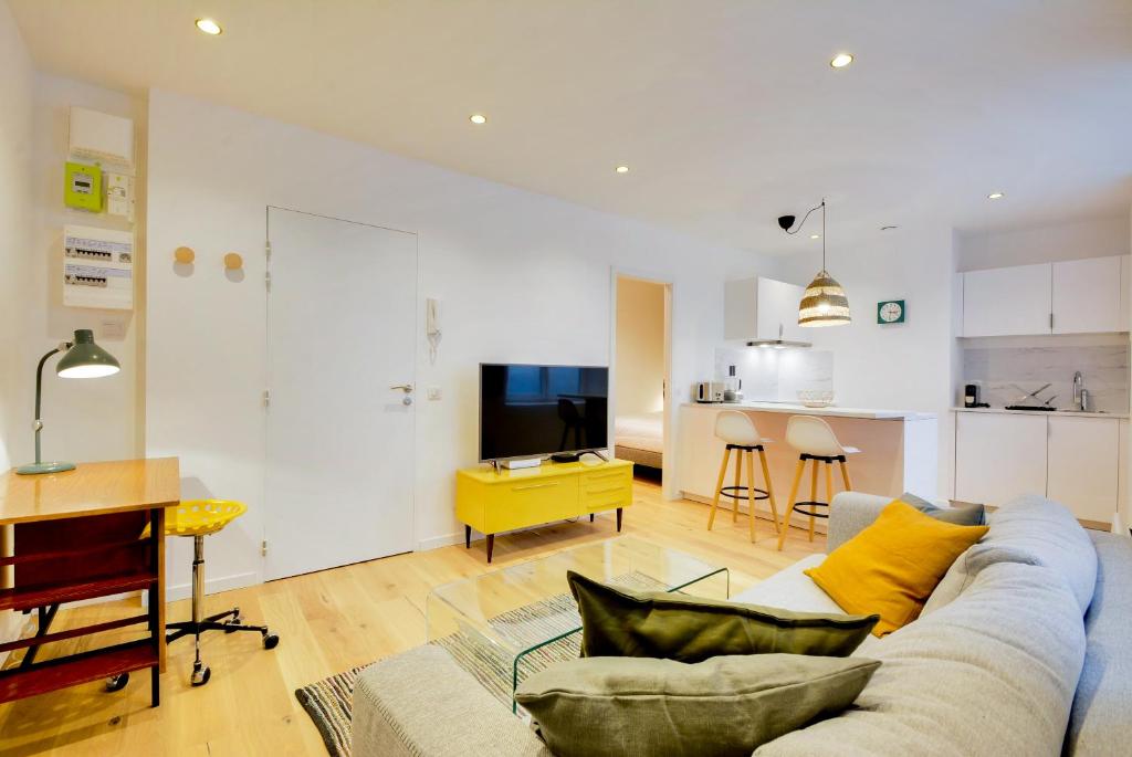 un salon avec un canapé et une cuisine dans l'établissement Le Cachet de la Craffe - Au cœur de Nancy, à Nancy