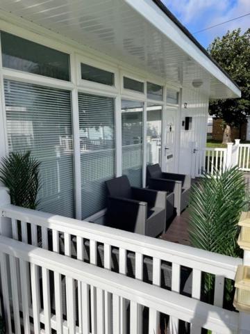a white porch with chairs on a house at 52 Cherry Park Chalet in Chapel Saint Leonards