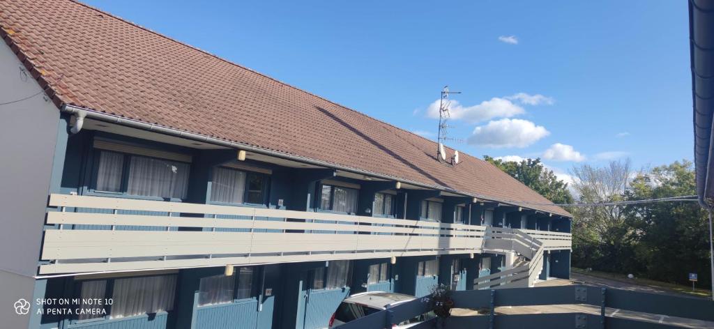 a building with a brown roof and a car parked outside at Kyriad Mulhouse Est - Lutterbach in Lutterbach