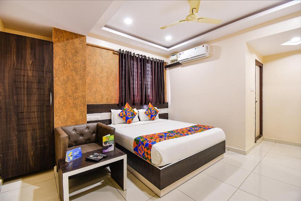 a bedroom with a bed and a chair in a room at FabHotel Rotano Suites Yelahanka in Bangalore