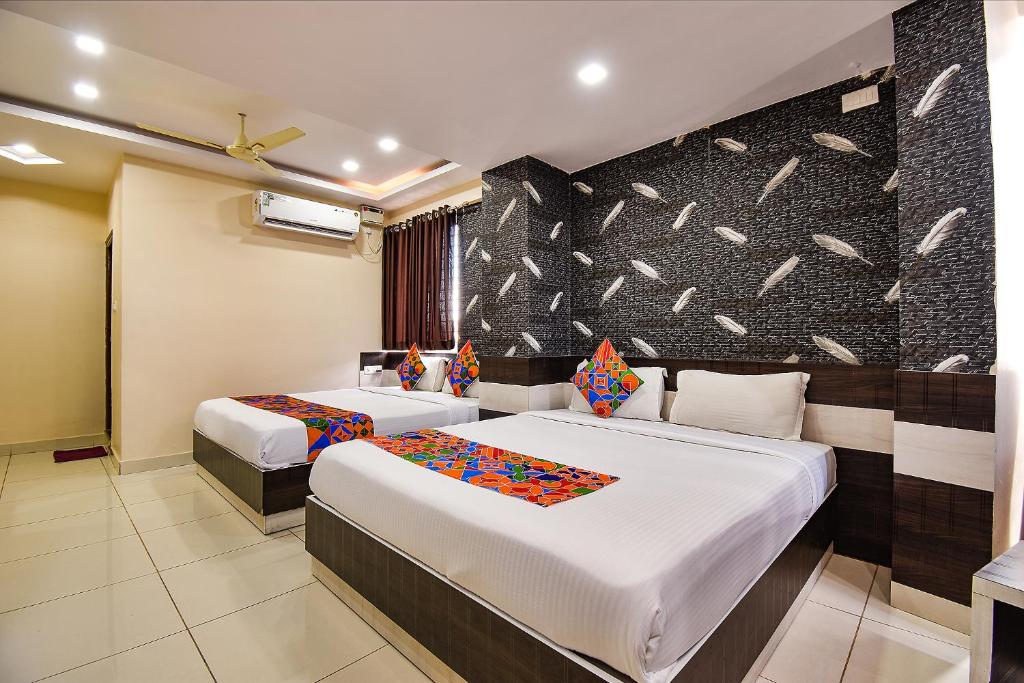 una camera d'albergo con due letti e una parete di FabHotel Rotano Suites - Yelahanka a Bangalore