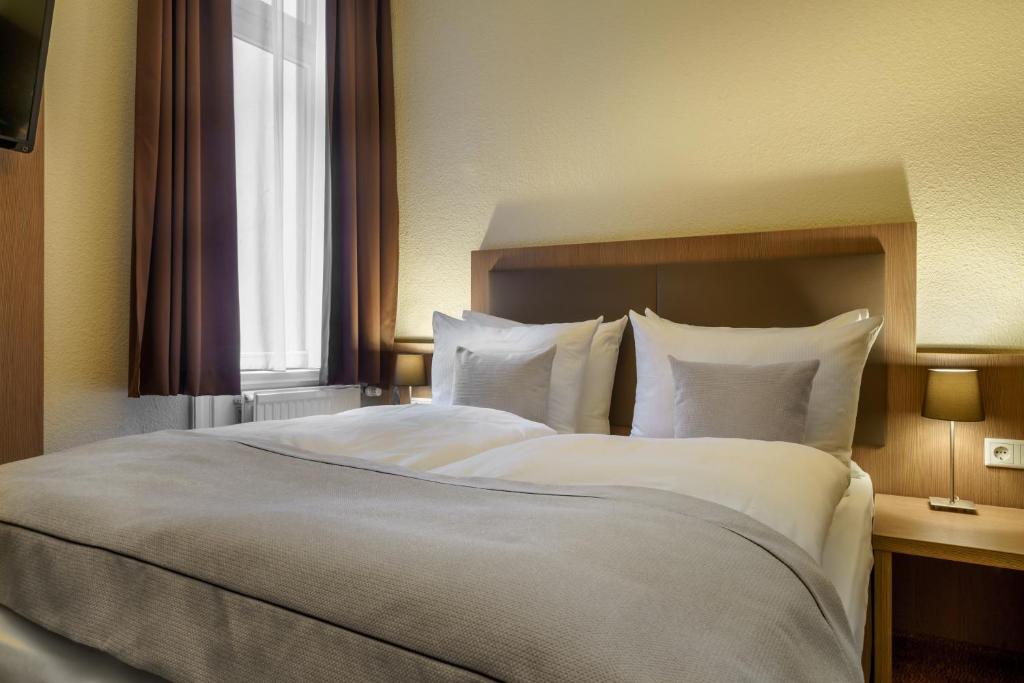 ein Schlafzimmer mit einem großen Bett mit weißer Bettwäsche und einem Fenster in der Unterkunft Novum Hotel Alster Hamburg St. Georg in Hamburg