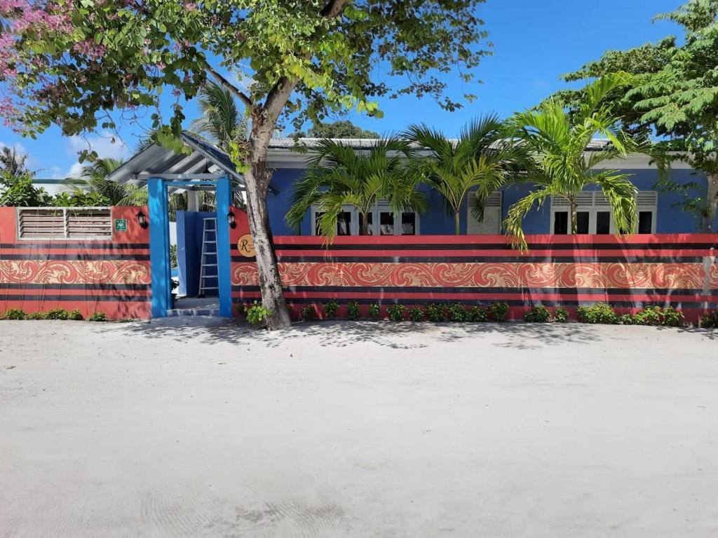a house with a colorful fence and a tree at Royal Beach Dhigurah in Dhigurah