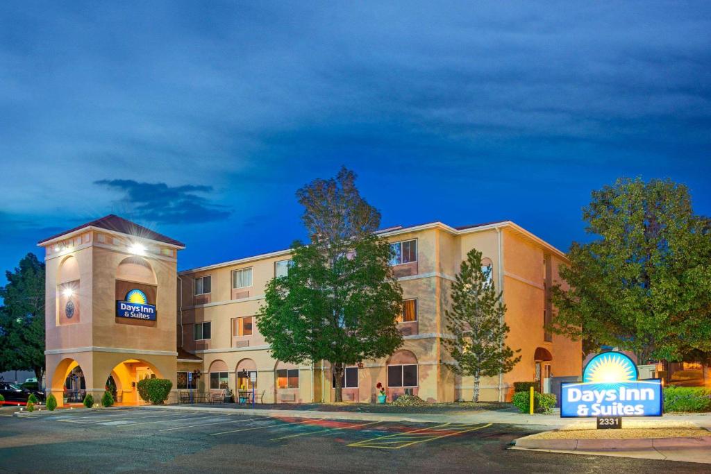 Days Inn & Suites by Wyndham Airport Albuquerque في ألباكيركي: مبنى الفندق امامه لافته