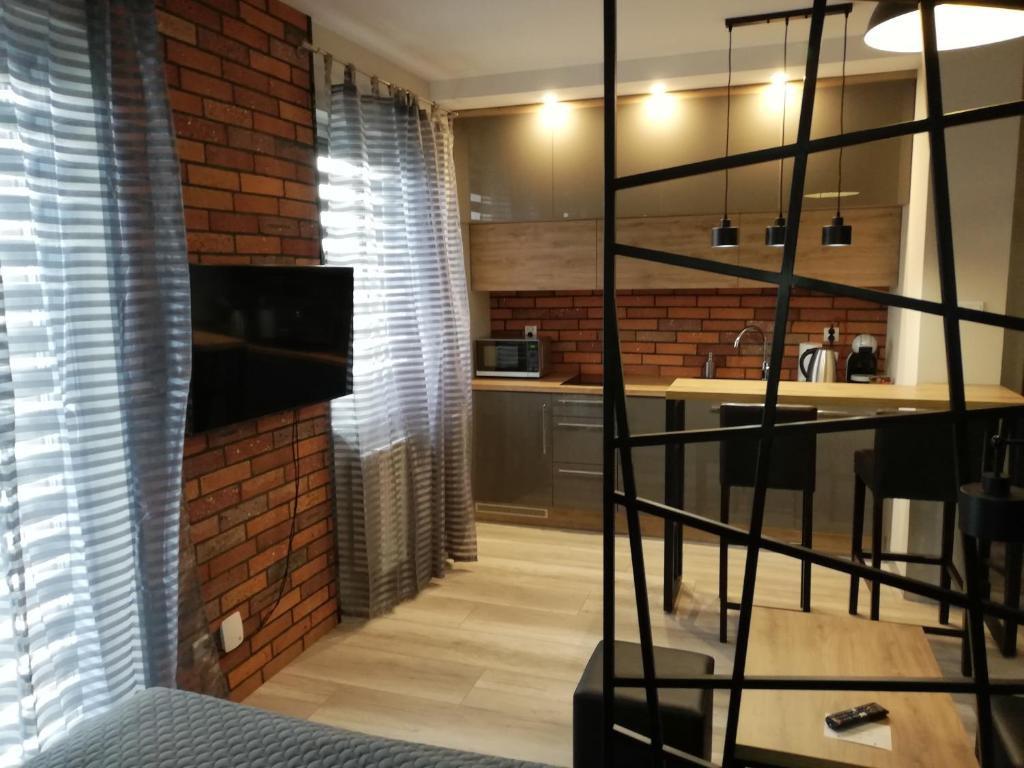 a living room with a brick wall and a kitchen at Czerwona Cegła Apartament in Zielona Góra