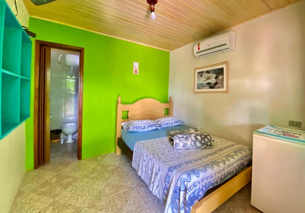 a bedroom with two beds and a green wall at Pousada Tia Maria in Paranaguá