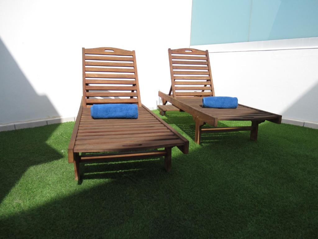 2 chaises en bois avec des coussins bleus assis sur l'herbe dans l'établissement NÁUTICO Suites, by Comfortable Luxury - Adults Only, à Corralejo