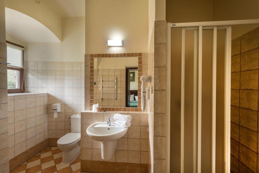 Tiled bathroom with shower, sink, and window providing natural light.