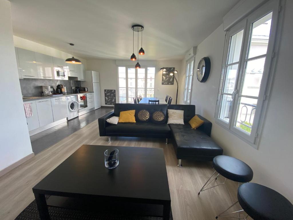 un salon avec un canapé noir et une table dans l'établissement T4 Disney Paris/Val d’Europe, à Serris